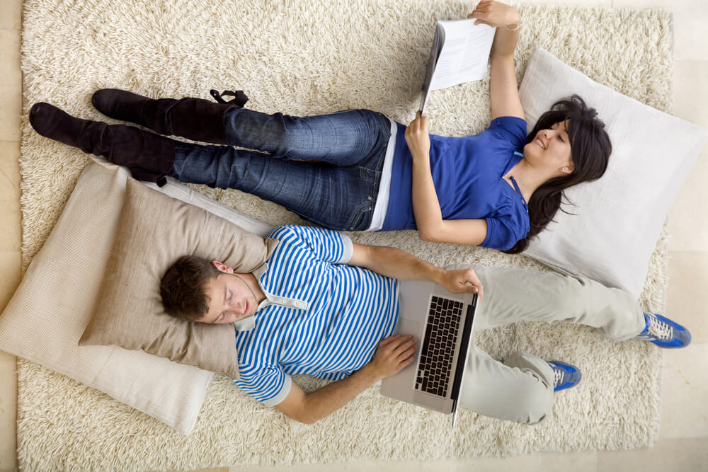 couple-relaxing-at-home-with-a-laptop-and-readin